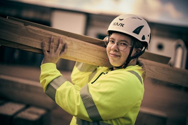 En person med reflexväst och hjälm som bär ved.