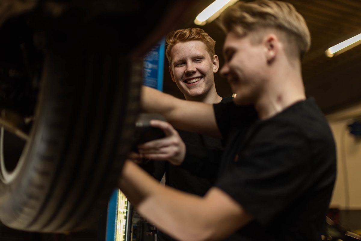Två elever mekar mkekar med en bil i en verkstad