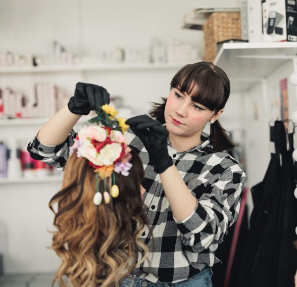 Elev på hår- och makeupstylist sätter blommor i en peruk.