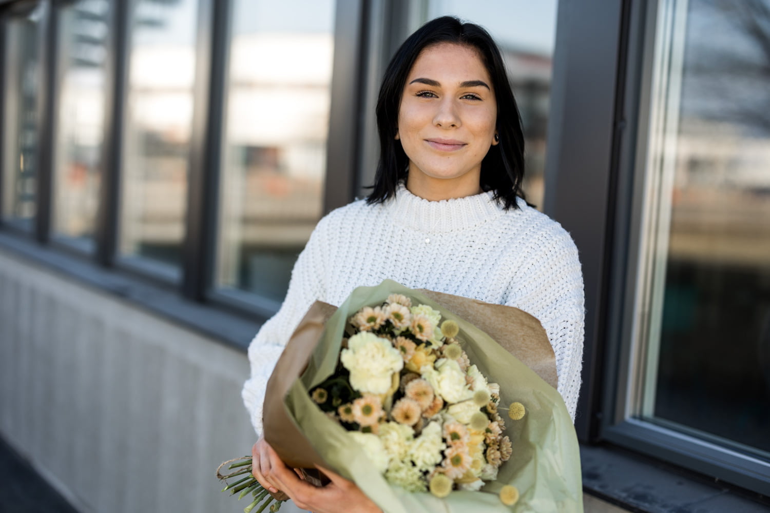 Porträttbild på Saga som ståe med stor bukett med blommor