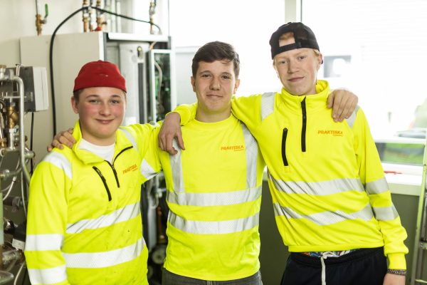 Tre elever med reflexkläder som håller om varandra