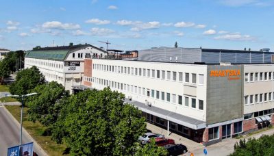Ett fotografi på en vit byggnad med Praktiska Gymnasiets logga på fasaden.