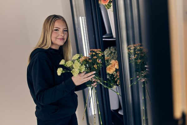 Floristelev på Praktiska som plockar blommor ur en blomkyl