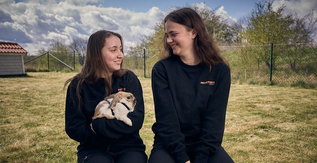 Två elever som håller i kaniner och skrattar.
