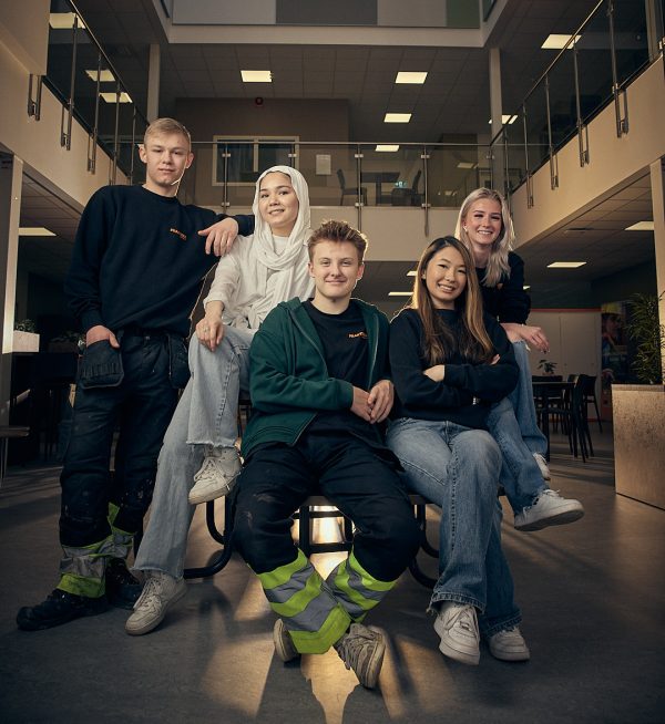 Fem elever på Praktiska som sitter runt ett bord och tittar in i kameran.