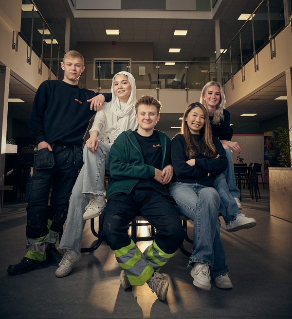Fem elever på Praktiska som sitter runt ett bord och tittar in i kameran.