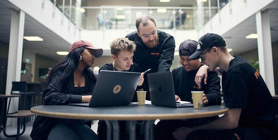 Fyra elever som studerar tillsammans med en lärare.