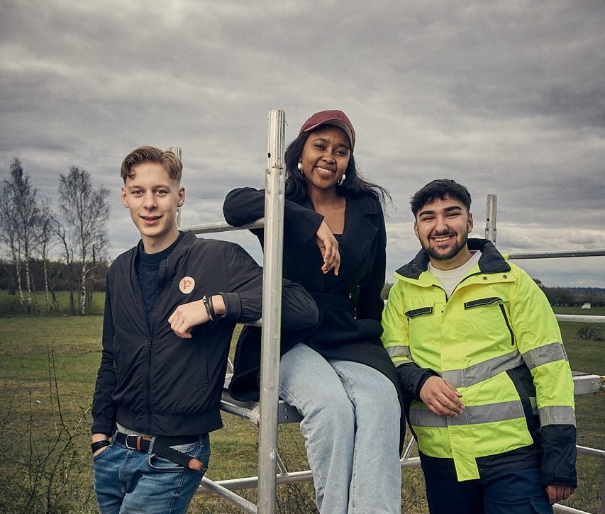 Tre elever på Praktiska vid en byggställning.