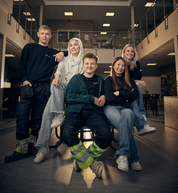 Fem elever på Praktiska som sitter runt ett bord och tittar in i kameran.