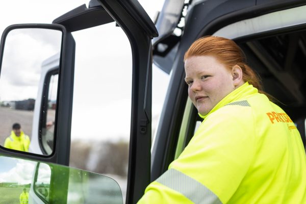 Transport-elev sitter i förarsätet på en lastbil med öppen dörr.