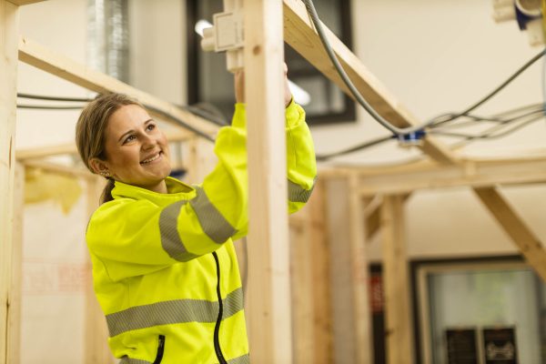 Elev på Praktiska Gymnasiet som drar el i en bygghall.