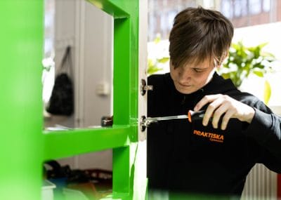 En elev skruvar med en skruvmejsel på ett dörrlås