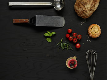 Föremål som representerar Restaurang- och livsmedelsprogrammet ligger utlagda på mörkt trä.