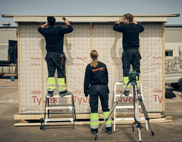 Tre elever som bygger på en stuga på skolgården.