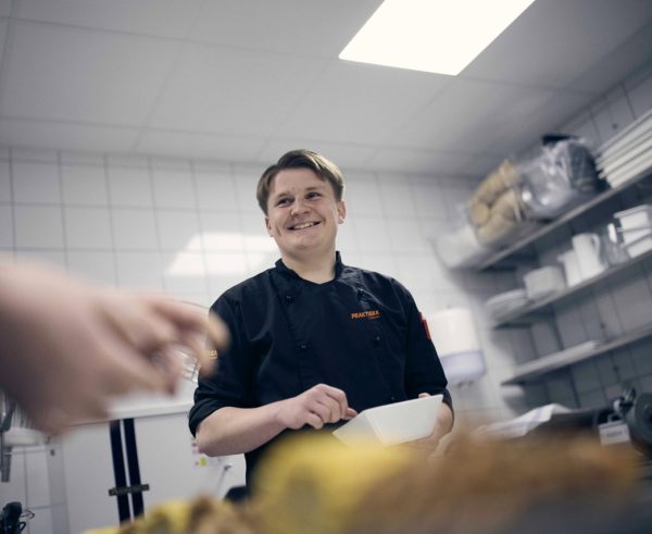 Elev som rör en sås i skolan restaurangkök.