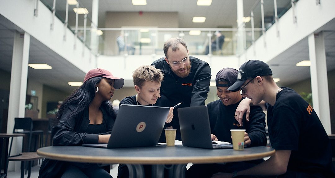 Fyra elever som pluggar i skolan och får hjälp av en lärare.
