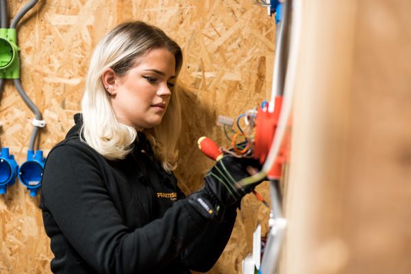 Elev på elteknik installerar el på en vägg.