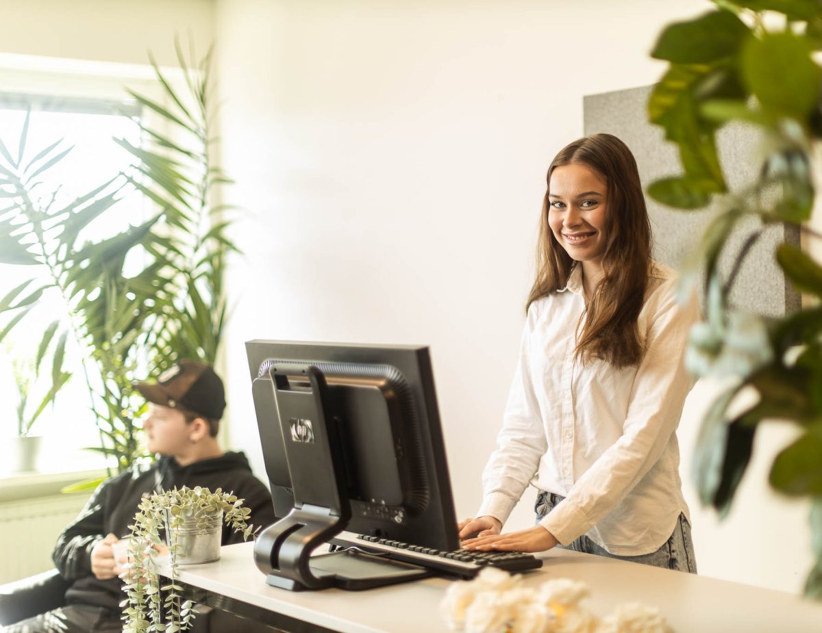 Elev som står vid en reception och tittar in i kameran