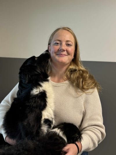 Ett personfoto på en kvinna som håller i en hund.